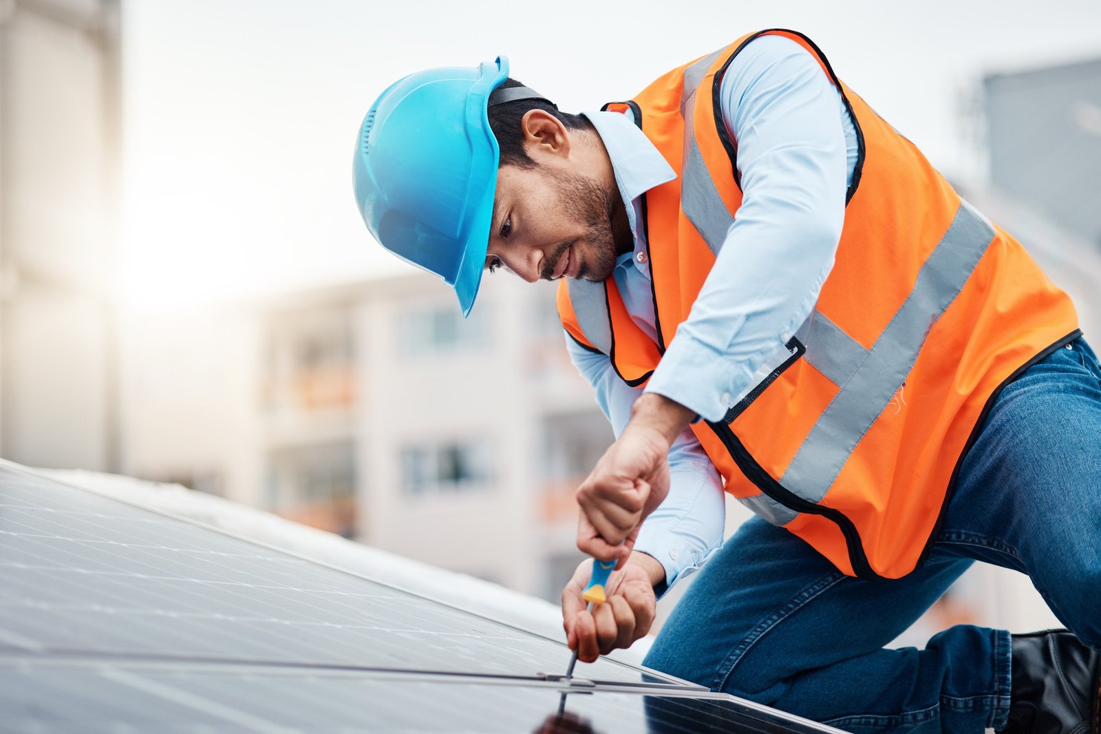 Solar panels, tool and male engineer on a rooftop doing maintenance or repairs with screwdriver. Re